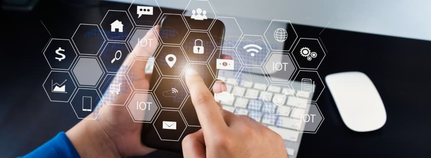 Osoba używa smartfona z ikonami, na tle klawiatury komputera.