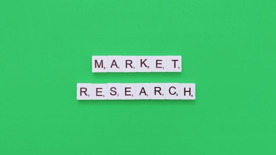 Napis "MARKET RESEARCH" ułożony z białych kafelków na zielonym tle.