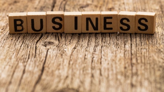 Drewniane kostki z literami układające się w słowo "BUSINESS" na drewnianym tle.