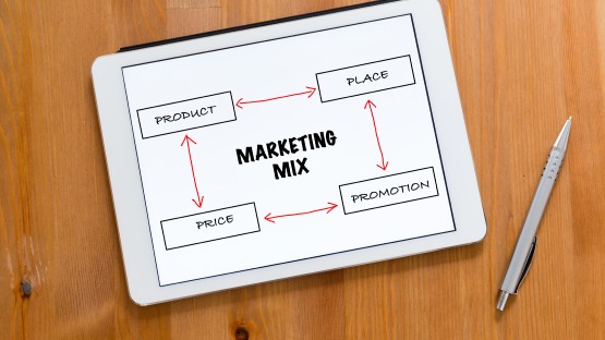 Schemat marketing mix: produkt, cena, promocja połączone strzałkami. Tablet i długopis obok.