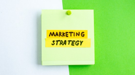 Zielona kartka z napisem "Marketing Strategy" na białym i zielonym tle.