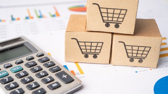 Obrazki wózków zakupowych na kartonowych kostkach, obok kalkulator czyli co to jest trade marketing.